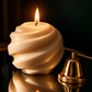 Enea, candela scultorea Design accesa con luce calda e spegnicandela dorato.